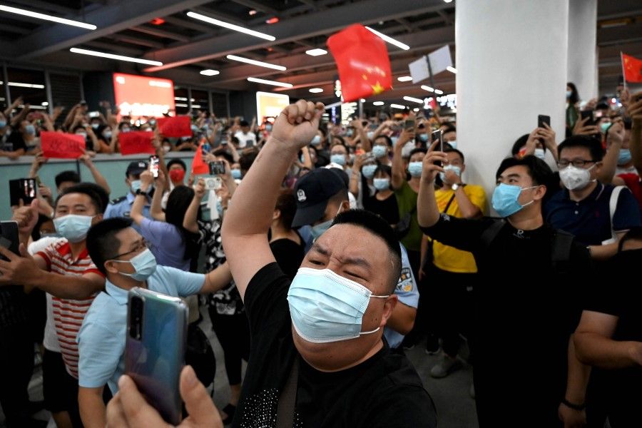 Supporters wave Chinese national flags as they wait for the arrival of Huawei executive Meng Wanzhou at the Bao'an International Airport in Shenzhen on 25 September 2021. (Noel Celis/AFP)
