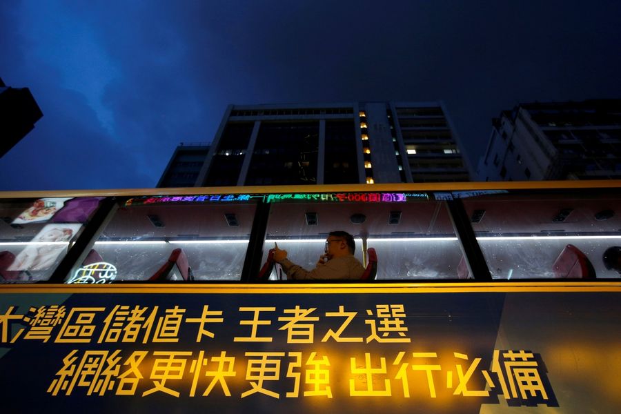 A man uses a phone as he travels on a bus with an advertisement for Greater Bay area SIM cards, in Hong Kong, China, August 19, 2019. (REUTERS/Willy Kurniawan/File Photo)