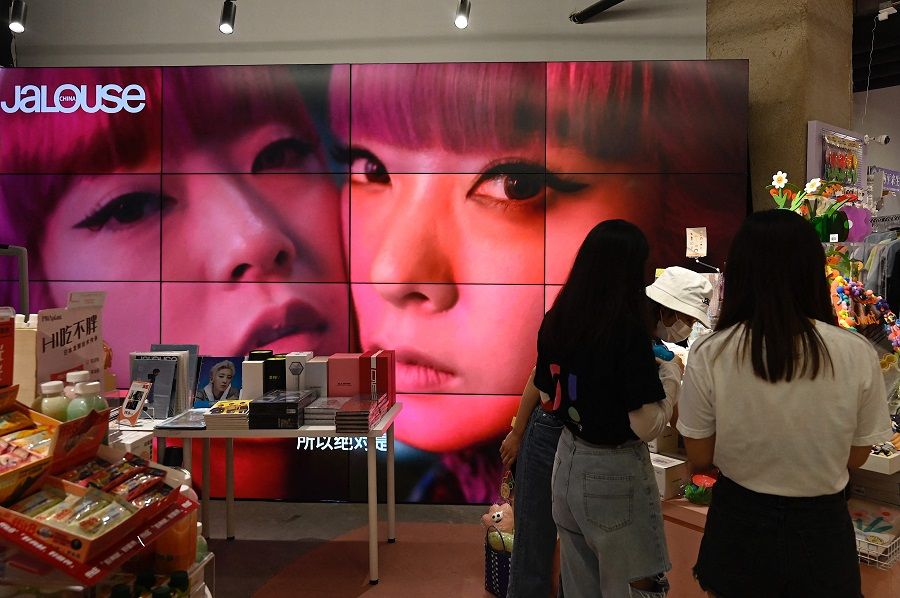 This file photo taken on 2 September 2021 shows a screen showing a video of overseas celebrity idols at a fan merchandise store at a shopping mall in Beijing, China. (Jade Gao/AFP)