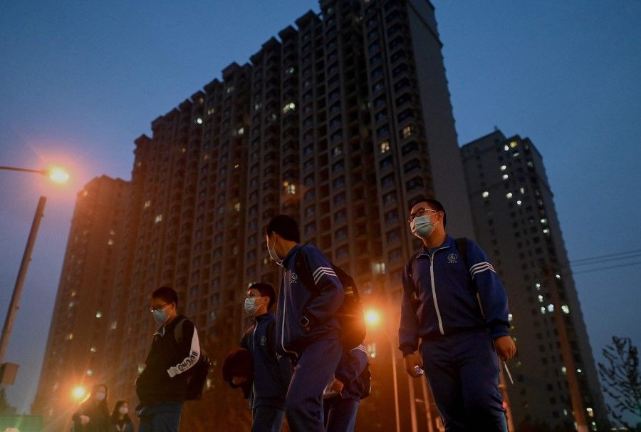 Students walk in front of a housing complex by Chinese property developer Evergrande in Beijing on 25 October 2021. (Noel Celis/AFP)