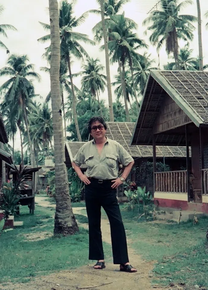 Chen Yingzhen posing beside a stilt house on an outlying island.