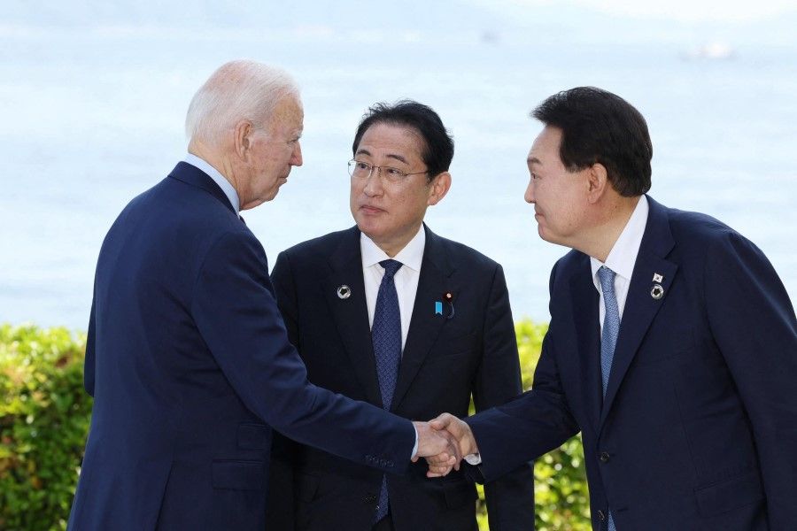 US President Joe Biden (left) shakes hands with South Korea's President Yoon Suk Yeol (right) as Japan's Prime Minister Fumio Kishida looks on ahead of a trilateral meeting on the sidelines of the G7 Summit Leaders' Meeting in Hiroshima on 21 May 2023. (AFP)