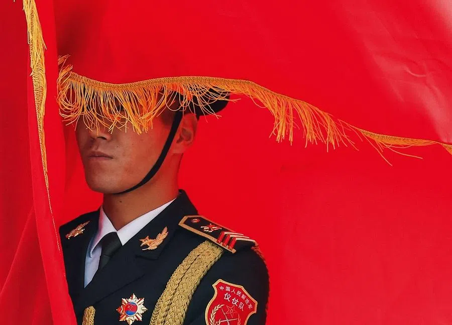 A Chinese People's Liberation Army (PLA) honour guard member holds a flag during a welcoming ceremony at the Great Hall of the People in Beijing on 12 November 2025.