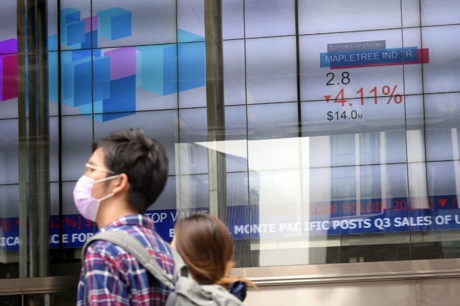 People pass an electronic stock board at The SGX Centre on 12 March, 2020. (SPH)