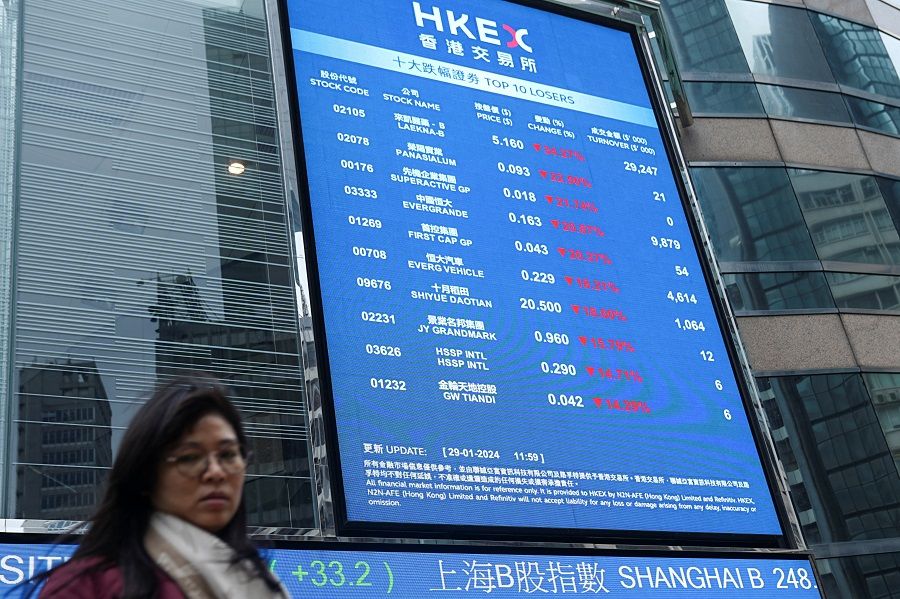 A woman walks in front of a screen displaying stock prices outside the Exchange Square in Hong Kong, China, on 29 January 2024. (Lam Yik/Reuters)