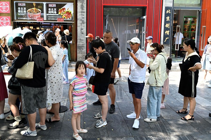People queue to enter a restaurant in Beijing, China on 15 August 2023. (Pedro Pardo/AFP)