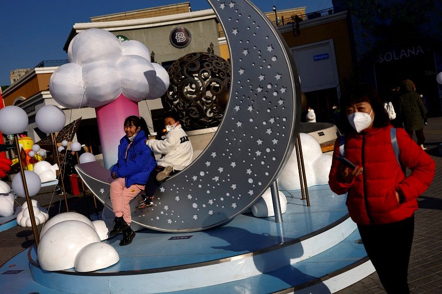 Children sit on an installation near a shopping area in Beijing, China, 3 February 2023. (Tingshu Wang/Reuters)