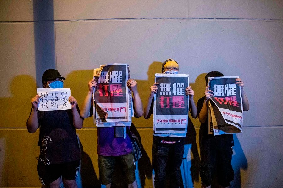 Supporters hold copies of the Apple Daily newspaper as Hong Kong pro-democracy media mogul Jimmy Lai is released on bail from the Mong Kok police station in Hong Kong on 12 August 2020, after his arrest under the new national security law. (Isaac Lawrence/AFP)