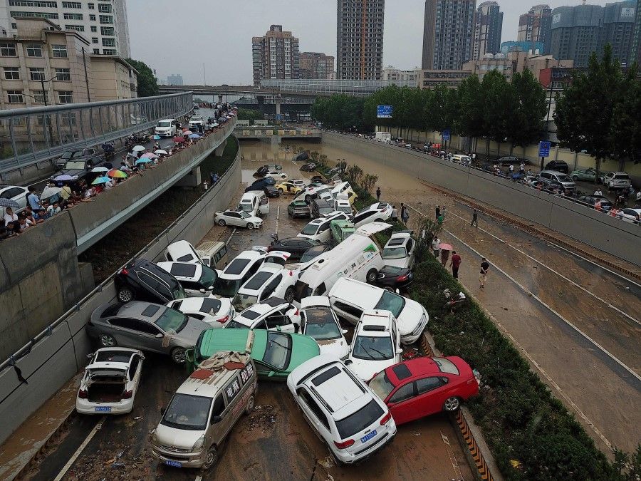 An aerial view shows cars sitting in floodwaters at the entrance of a tunnel after heavy rains hit the city of Zhengzhou in China's central Henan province on 22 July 2021. (Noel Celis/AFP)
