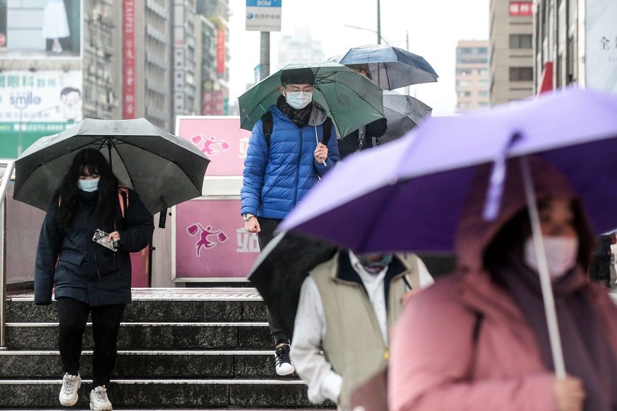 Pedestrians wearing protective masks and holding umbrellas walk along a road in Taipei, Taiwan, on 11 January 2021. (I-Hwa Cheng/Bloomberg)