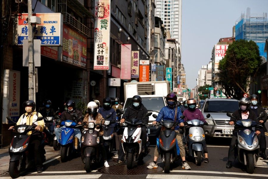 People riding scooters wait at a traffic light on the street during morning rush hour in Taipei, Taiwan, 11 April 2023. (Carlos Garcia Rawlins/Reuters)