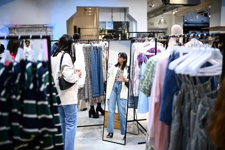 A woman browses through clothes displayed at Chinese fashion brand Shein's pop-up store in Paris, France, on 4 May 2023. (Christophe Archambault/AFP)