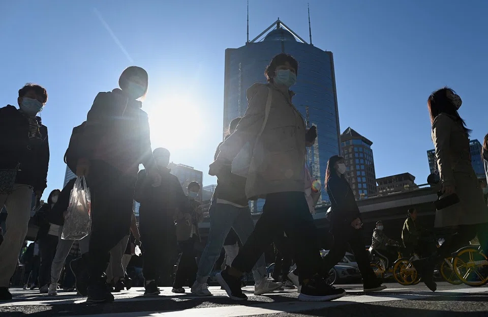 People walk along a street in Beijing, China, on 12 October 2021. (Noel Celis/AFP)