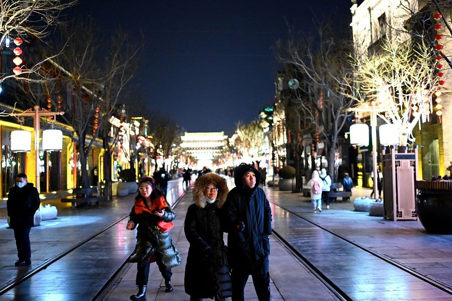 People walk along Qianmen street in Beijing, China, on 31 January 2022. (Noel Celis/AFP)
