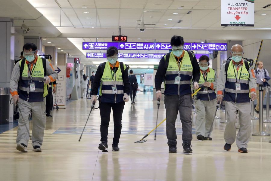 Masked workers disinfect a passenger thoroughfare at the Taoyuan International Airport on 22 January 2020, after Taiwan reported its first case of the 2019-nCoV on 21 Jan. (Chen Chi-chuan/AFP)