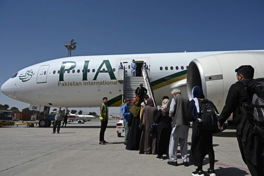 Passengers board a Pakistan International Airlines (PIA) flight, the first commercial international flight since the Taliban retook power last month, at the airport in Kabul on 13 September 2021. (Aamir Qureshi/AFP)