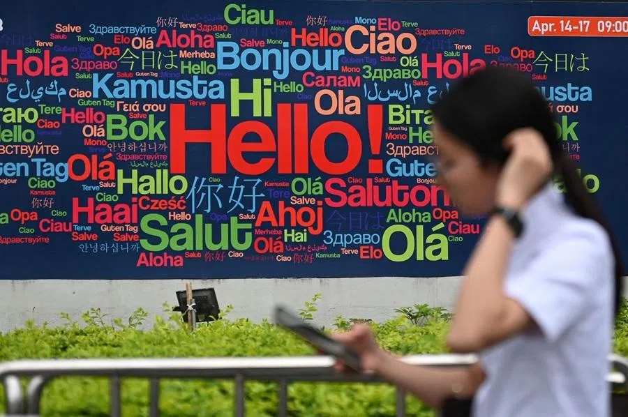 A woman walks past a billboard along a street in Guangzhou, in southern China's Guangdong province, on 14 April 2026.