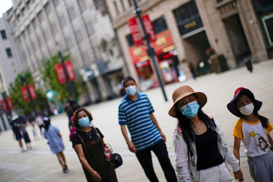 People wearing protective face masks walk on a street in Shanghai, China, 25 August 2021. (Aly Song/Reuters)