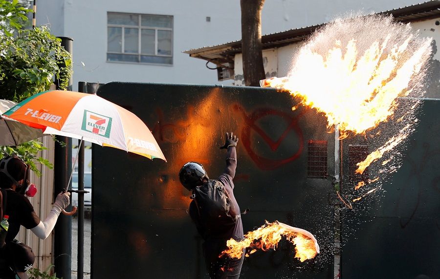 An anti-government demonstrator throws a petrol bomb towards Tsim Sha Tsui Police Station during a protest march in Hong Kong, China, 20 October 2019. (Tyrone Siu/Reuters)
