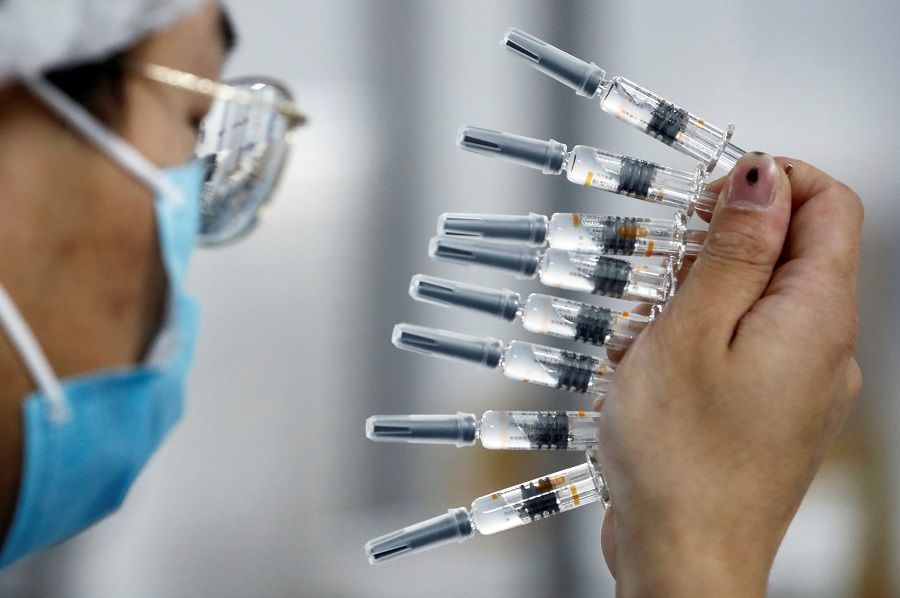 A worker performs a quality check in the packaging facility of Chinese vaccine maker Sinovac Biotech, developing an experimental Covid-19 vaccine, during a government-organised media tour in Beijing, China, 24 September 2020. (Thomas Peter/Reuters)
