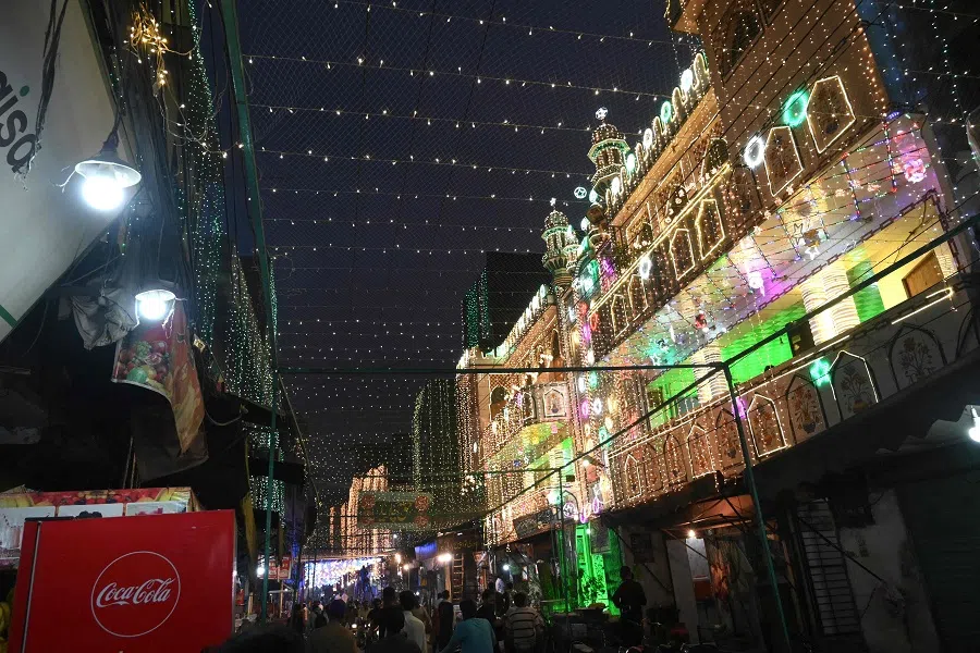 People walk past a decorated mosque during the celebrations for Eid-e-Milad-un-Nabi which is the birthday of the Prophet Mohammad, in Lahore, Pakistan, on 18 October 2021. (Arif Ali/AFP)