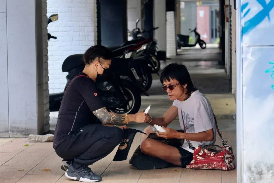A homeless person (right) receives free face masks and a bottle of alcohol from a local resident in Ximen, a commercial zone, at the Wanhua District in Taipei on 19 May 2021. (Sam Yeh/AFP)
