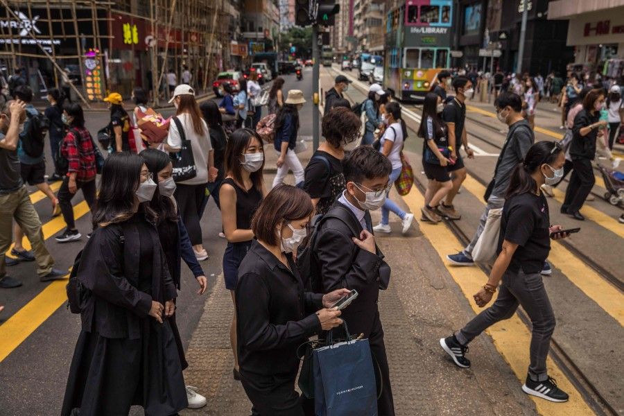 People cross a street in Hong Kong on 8 May 2022. (Dale de la Rey/AFP)
