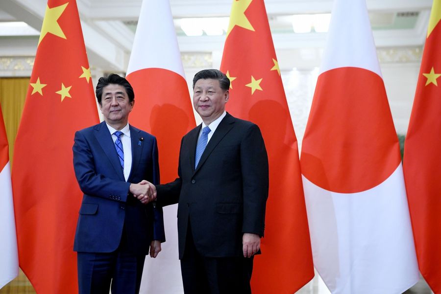 Japan's Prime Minister Shinzo Abe (left) shakes hands with China's President Xi Jinping at the Great Hall of the People in Beijing on 23 December 2019. (Noel Celis/POOL/AFP)