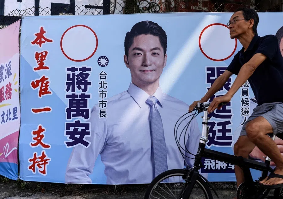 A man rides a bicycle past a campaign banner featuring the KMT Taipei mayoral candidate Chiang Wan-an in Taipei on 15 October 2026.