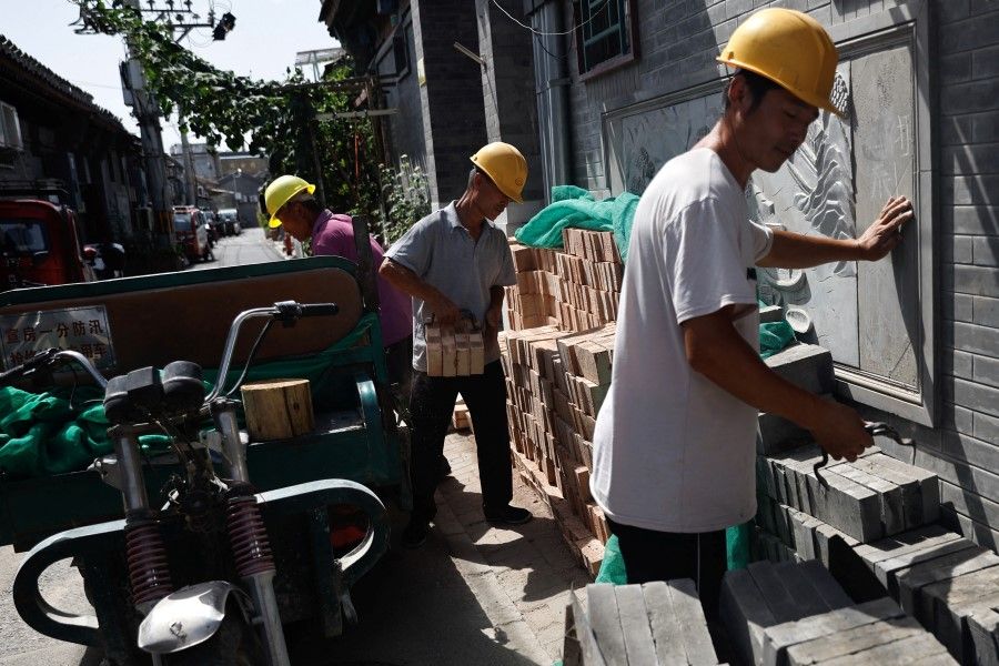 Construction workers work amid the orange alert for heatwave, at a hutong alley in Beijing, China, on 5 July 2023. (Tingshu Wang/Reuters)