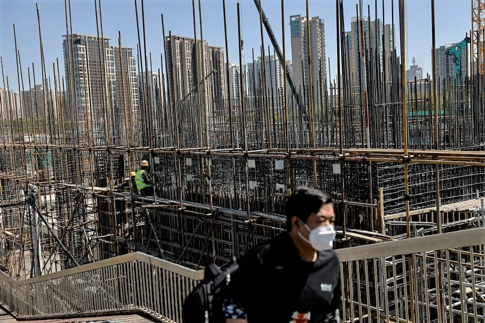 A man walks on an overpass near a construction site of a subway station in Beijing, China, 18 April 2023. (Tingshu Wang/Reuters)