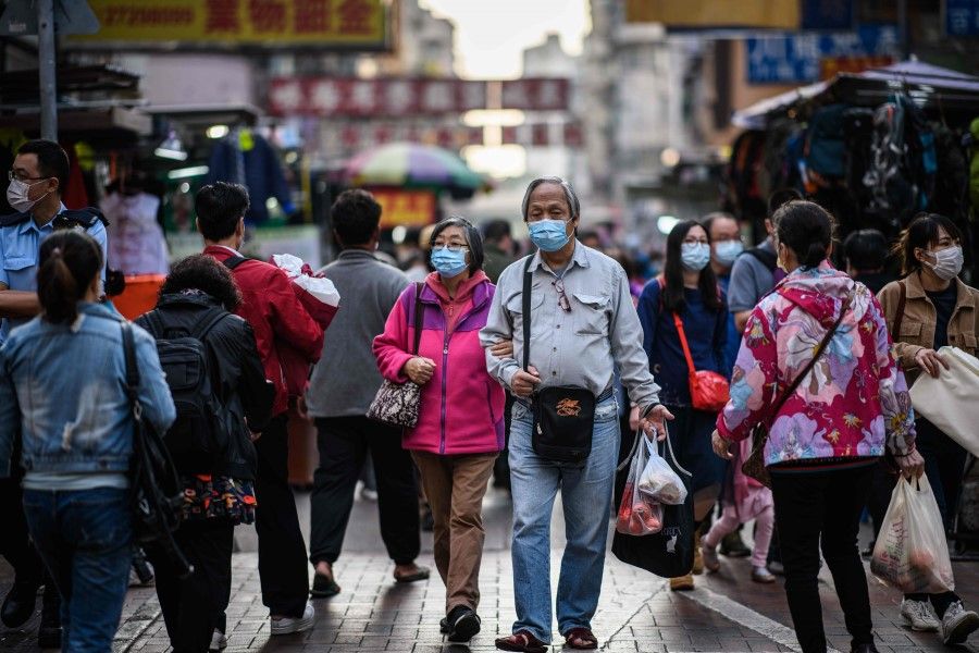 Pedestrians carry their shopping as they walk in the Sham Shui Po district of Kowloon in Hong Kong on 27 January 2021. (Anthony Wallace/AFP)