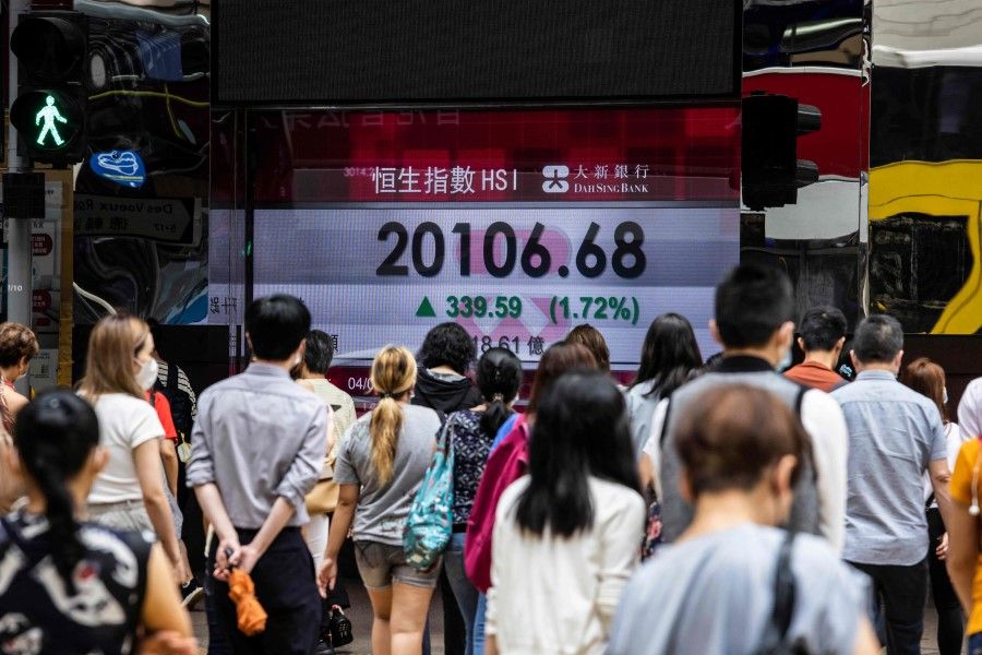 People walk past an electronic display of the Hang Seng Index in Hong Kong on 4 August 2022. (Isaac Lawrence/AFP)