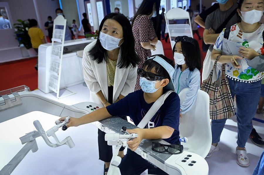 A child operates a robotic arm for surgery at the 2022 World Robot Conference in Beijing, China, on 18 August 2022. (Wang Zhao/AFP)
