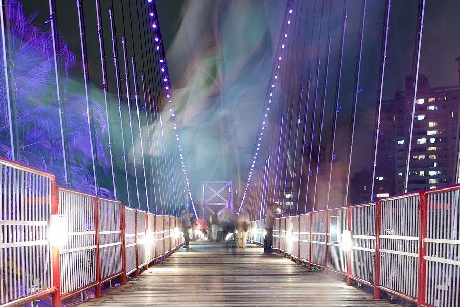 This picture taken at slow shutter speed on 25 April 2023 shows people walking through a suspension bridge at the Bitan scenery site in New Taipei City, Taiwan. (Sam Yeh/AFP)