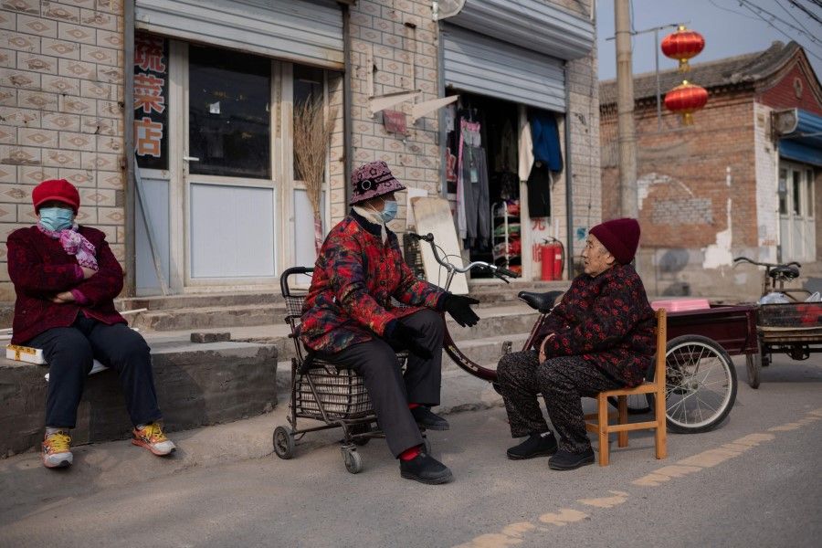 Elderly women chat on a street in Beijing, China on 6 March 2021. (Nicolas Asfouri/AFP)