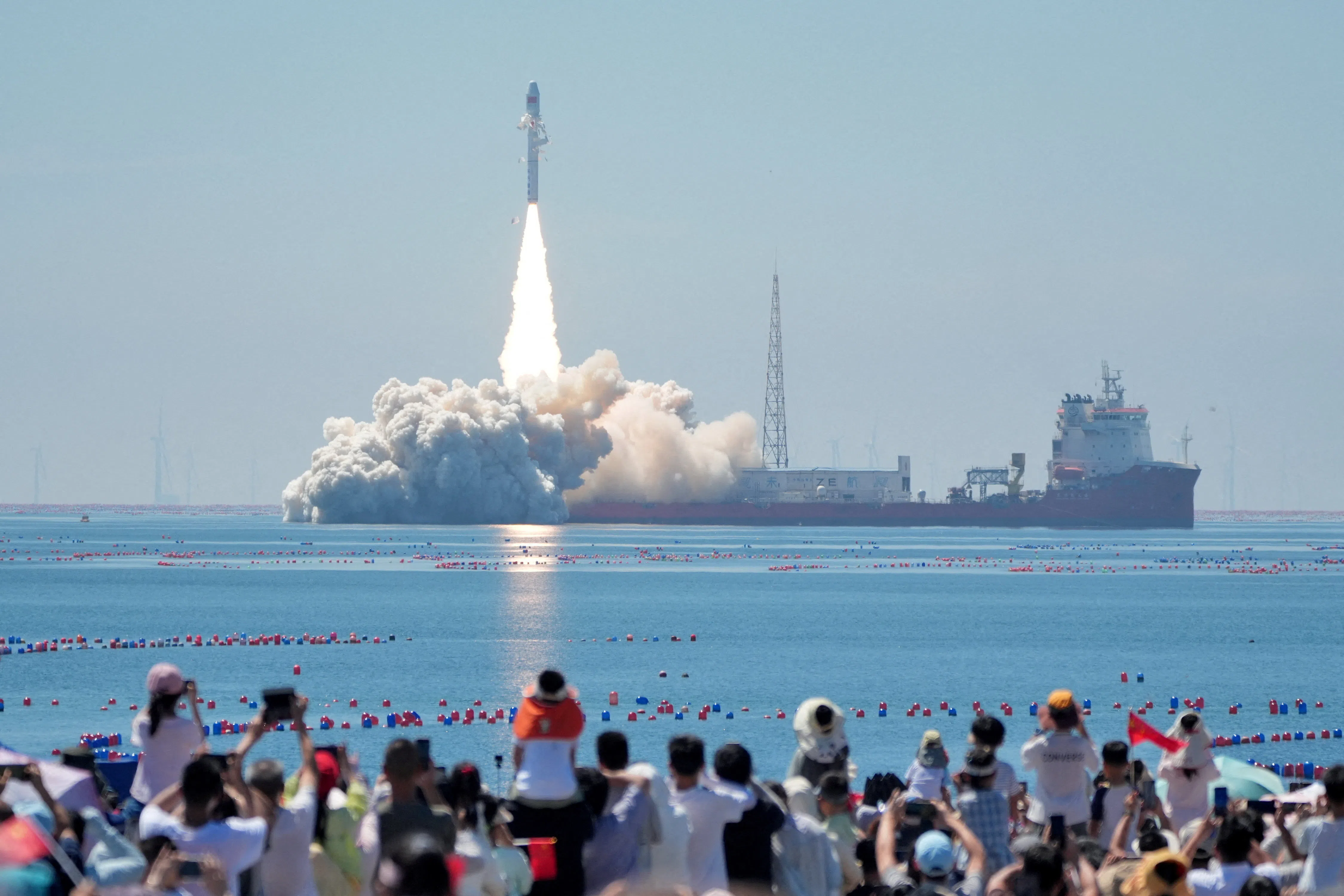 People watch a Smart Dragon-3 (SD-3) carrier rocket carrying Oriental Smart Eye hyperspectral satellites 01 and 02 launching from waters off the coast of Haiyang, in Shandong province, China, on 5 August 2026.