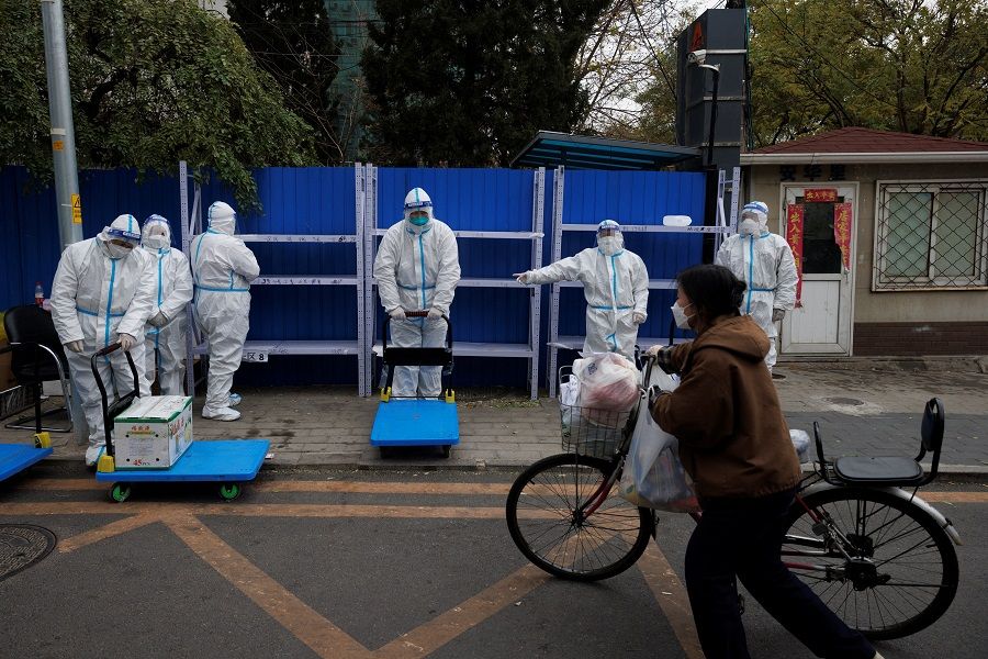 A woman delivers food to a residential compound that is under lockdown as Covid-19 outbreaks continue in Beijing, China, 28 November 2022. (Thomas Peter/Reuters)