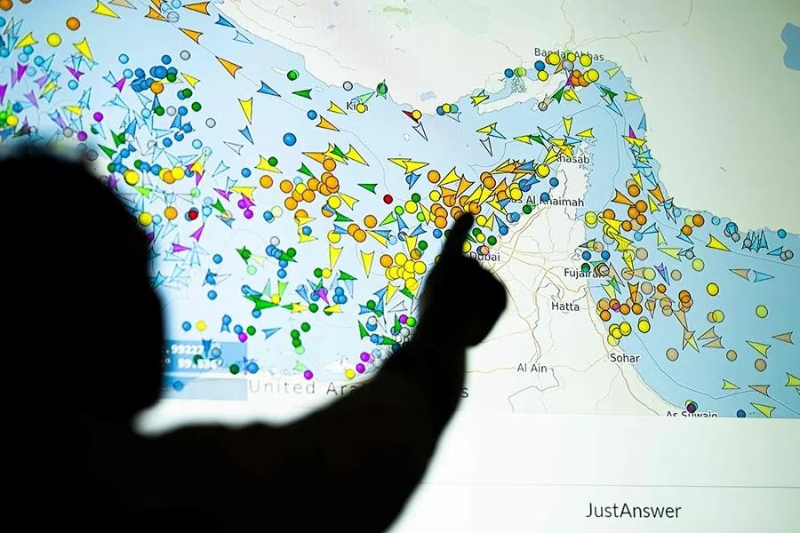 A photo illustration taken in Nicosia on 4 May 2026, shows a person in front of a large screen displaying vessel movements in the Strait of Hormuz on a ship tracking website. (AFP)