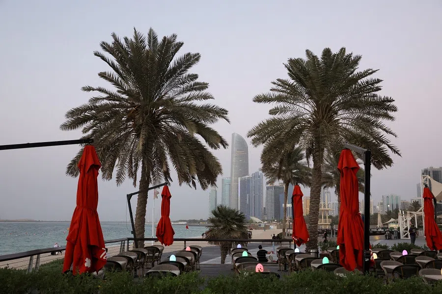 People relax near palm trees as the skyline is seen in the background in Abu Dhabi, United Arab Emirates, on 27 September 2023. (Amr Alfiky/Reuters)
