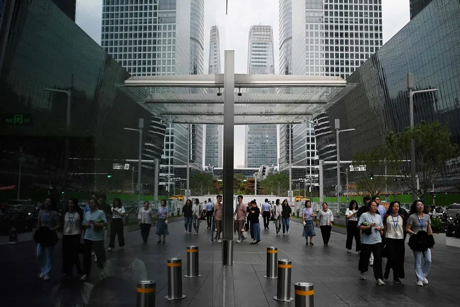 Office workers walk past buildings in Beijing’s central business district on 31 July 2025. (Greg Baker/AFP)