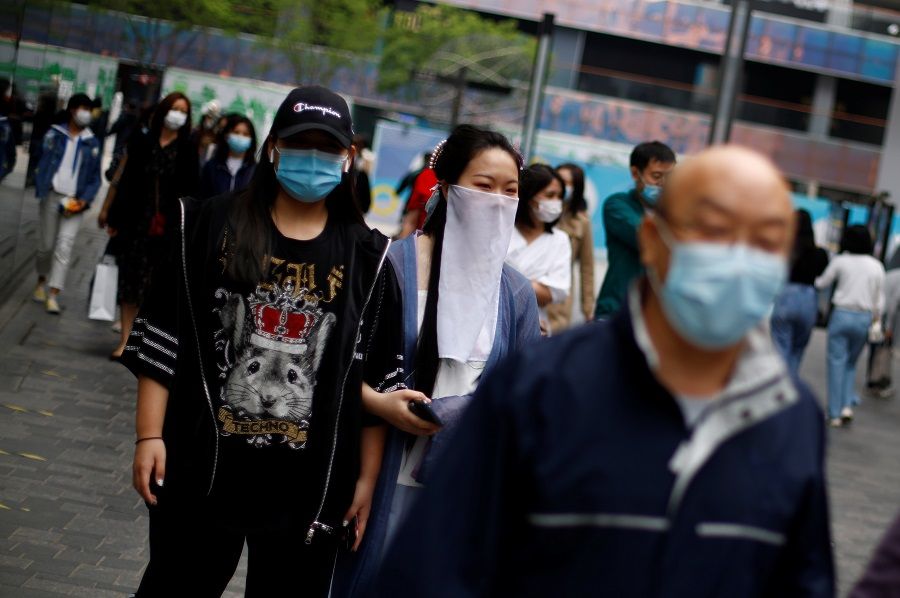 People wearing face masks walk in a shopping district, amid the Covid-19 outbreak, in Beijing, China, on 4 May 2020. (Thomas Peter/Reuters)