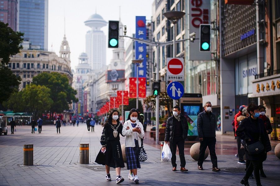 People wearing face masks walk at a shopping area in Shanghai, China, 27 January 2021. (Aly Song/Reuters)