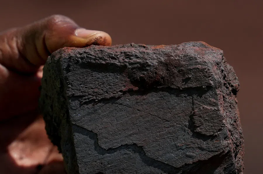 A man holds a lump of iron ore at the blocks three and four of the Simandou mine, one of the largest high-grade iron ore deposits, run by Rio Tinto and partners' joint venture, SimFer, in the Nzerekore region, Guinea, on 5 November 2025.