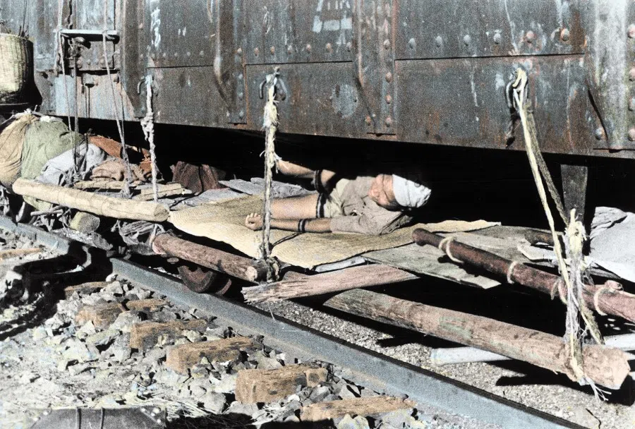 In 1938, refugees set up wooden beds under a train that has pulled into Sichuan. Chinese civilians fled to Chongqing by any means they could find over land or water.