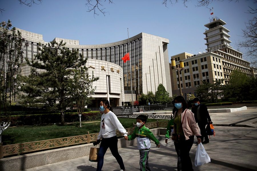 People wearing face masks walk past the headquarters of the People's Bank of China (PBOC), 4 April 2020. (Tingshu Wang/File Photo/Reuters)