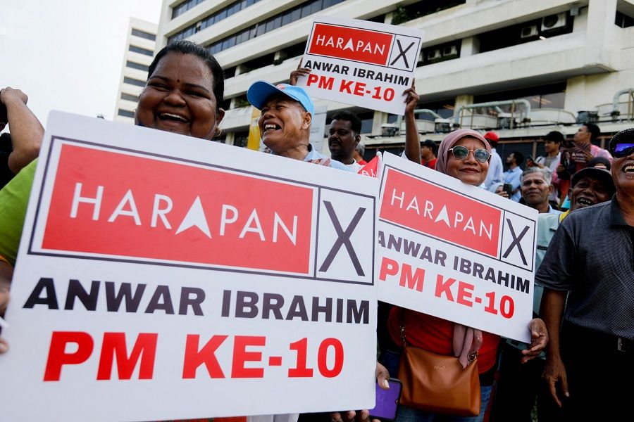 Anwar Ibrahim's supporters hold placards with 'ANWAR IBRAHIM PM KE-10' written on them outside the National Palace in Kuala Lumpur, Malaysia, 24 November 2022. (Hasnoor Hussain/Pool/Reuters)