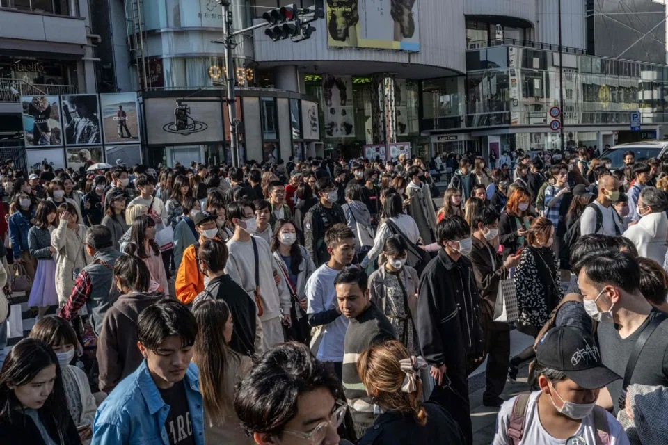 People cross a street in Omotesando shopping district of Tokyo on 9 April 2023. (Yuichi YamazakiAFP)