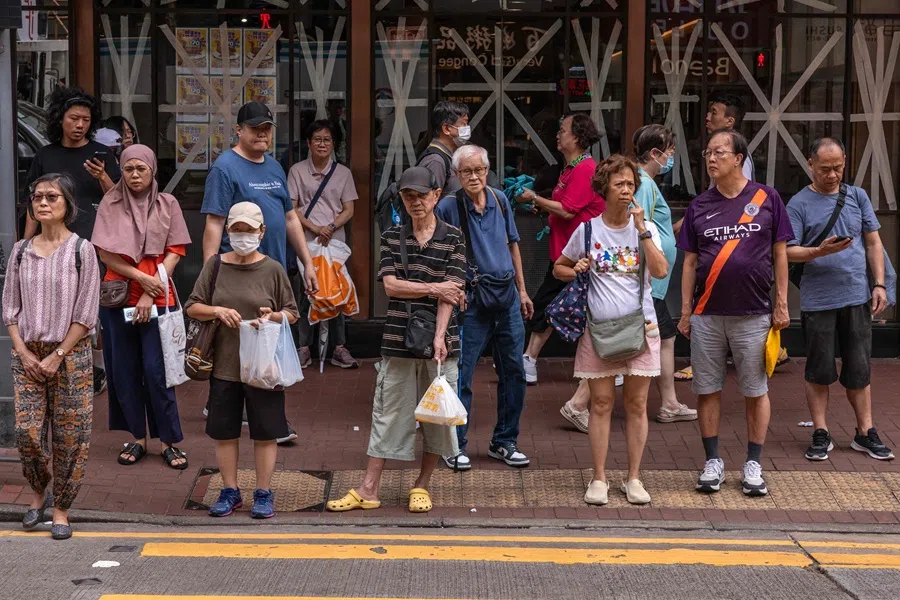 People wait to cross a street in Hong Kong on 23 September 2025. (Dale de la Rey/AFP)