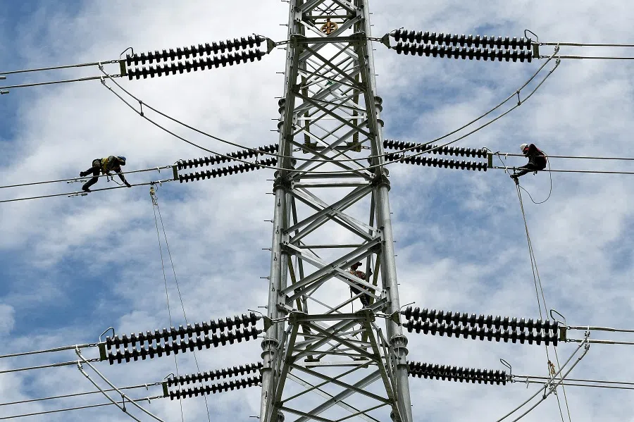 Workers assemble power cables to connect a substation in Phnom Penh, Cambodia, on 2 May 2022. (Tang Chhin Sothy/AFP)